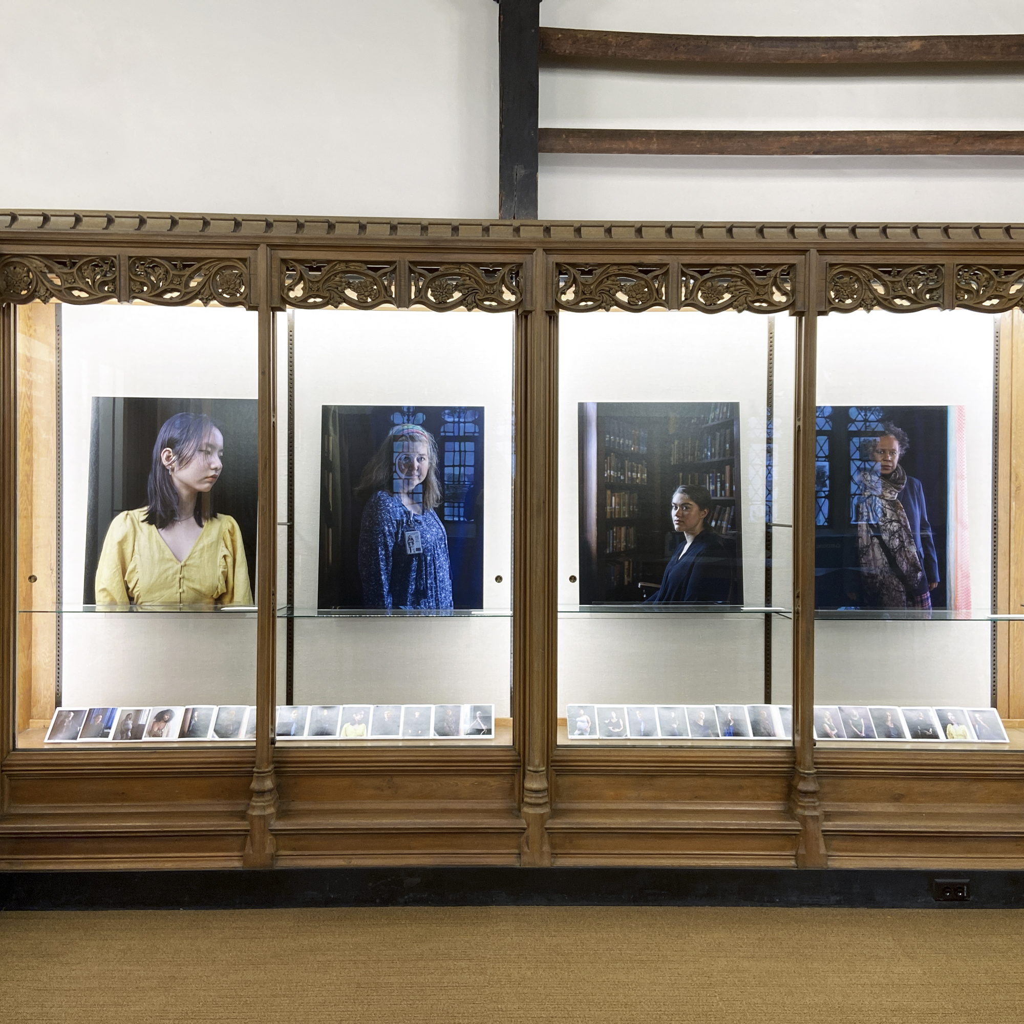 Intstallation photo of the 12 Portraits exhibit at Yale's Sterling Memorial Library showing four photographic portraits at 34 by 46 inches, set inside glassed in cases with ornate wooden molding.